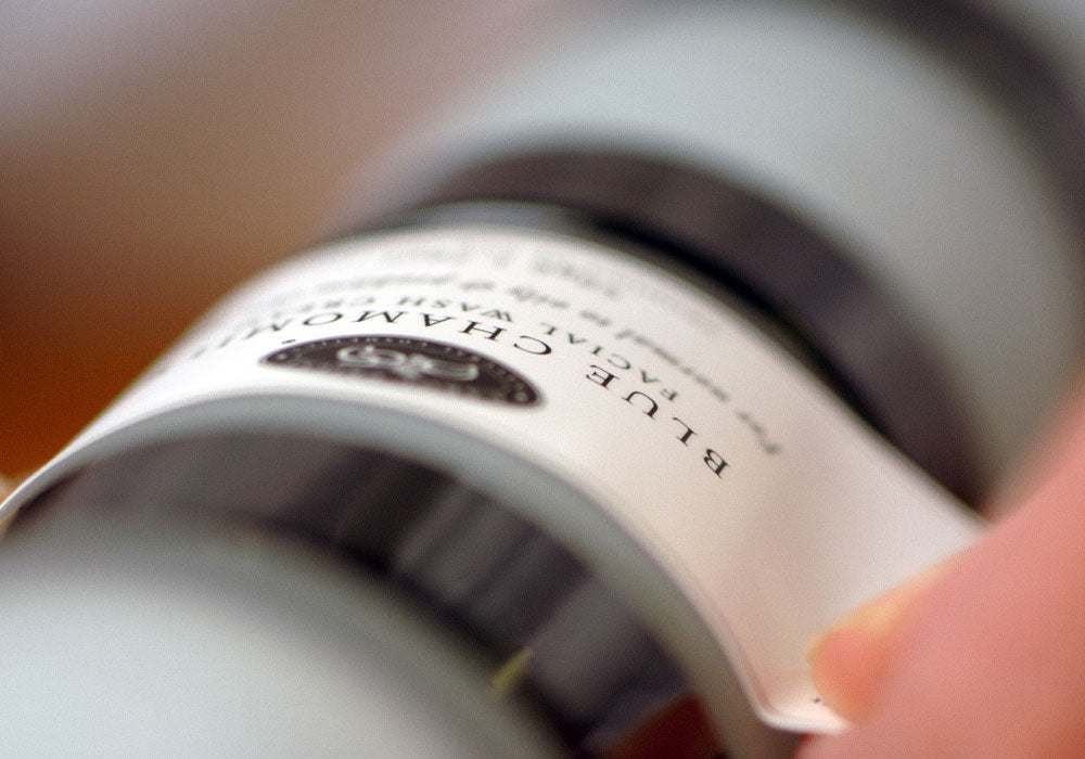 Image displaying the labeling process for Carol Priest's Blue Chamomile Facial Wash Cream, showcasing quality control and production procedures.